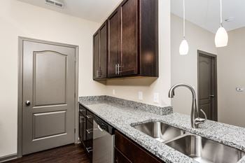 A kitchen with a sink and wooden cabinets and a door